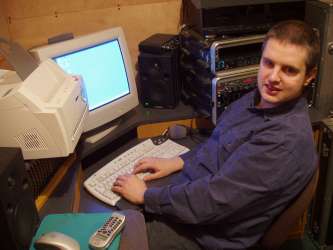 Picture of Phil smiling at a PC in his studio